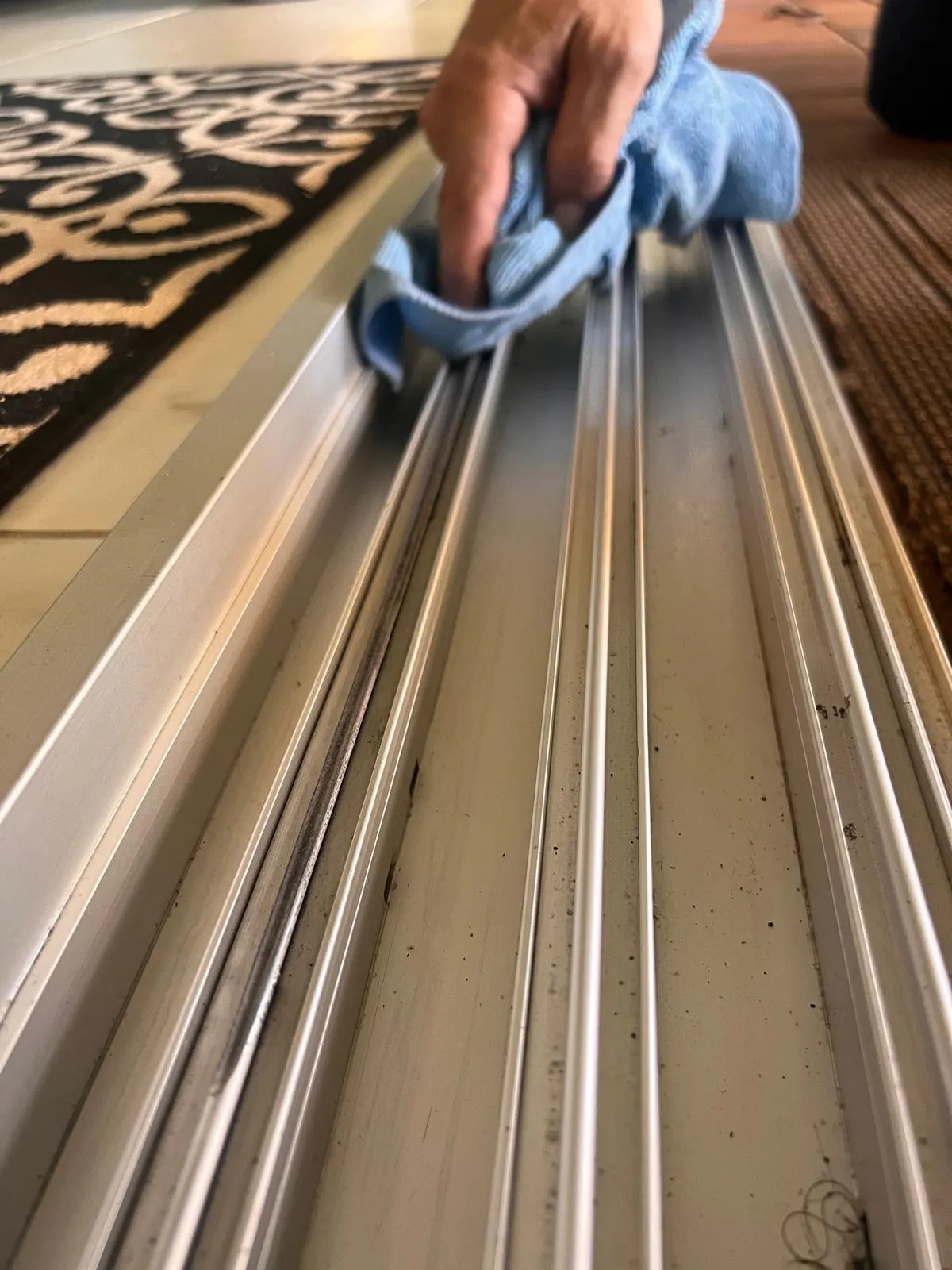 Technician cleaning a sliding door track during a patio door tune-up service