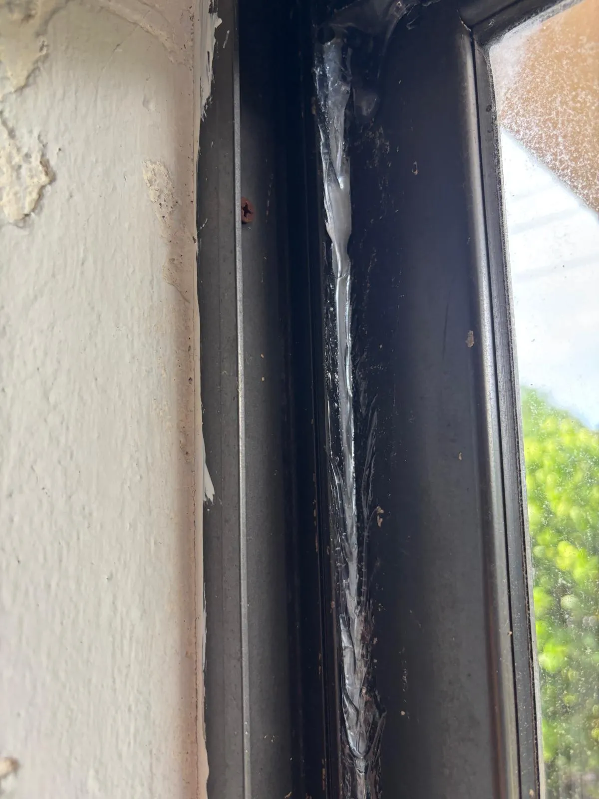 Damaged sliding door track with sealant buildup before repair