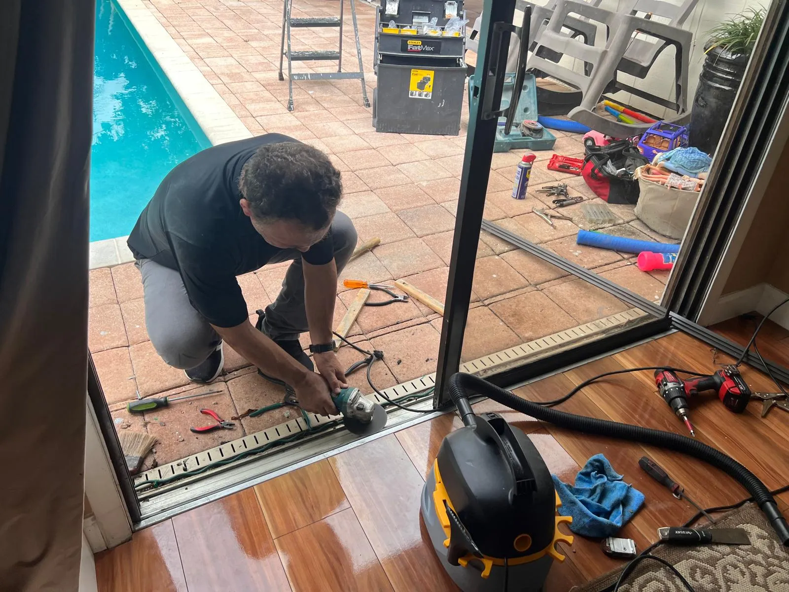 All Star Sliding Doors technician grinding and repairing a sliding glass door track at a customer home by the pool