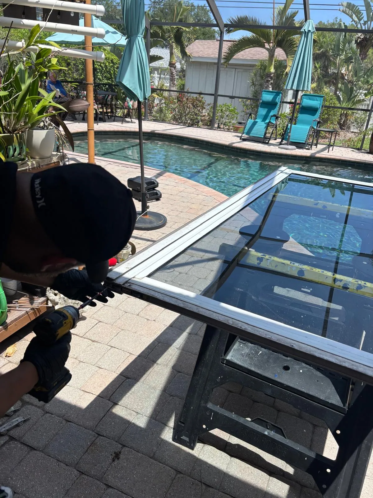 All Star Sliding Doors technician replacing rollers on a sliding glass door panel at a Florida home with pool in background